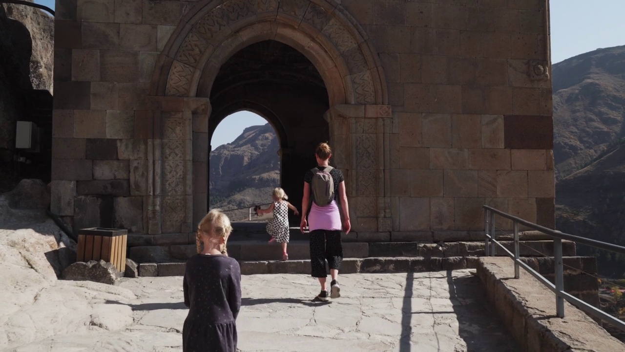 年轻的母亲带着两个金发的小女儿走在瓦尔齐亚的洞穴城视频素材