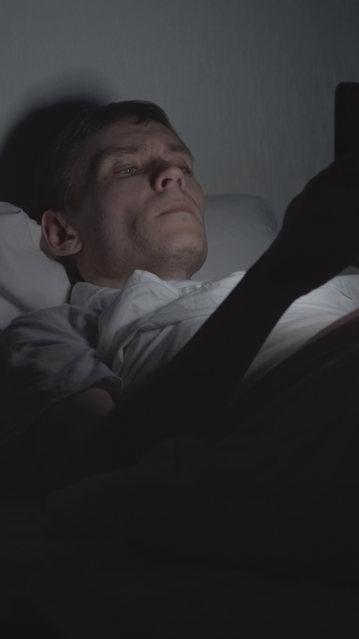 男人晚上躺在床上使用智能手机视频素材