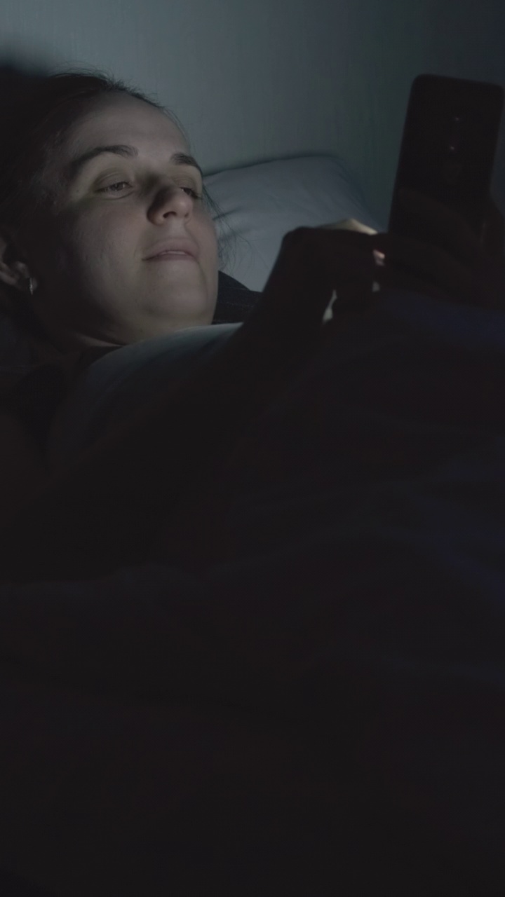 女人晚上躺在床上玩手机视频素材