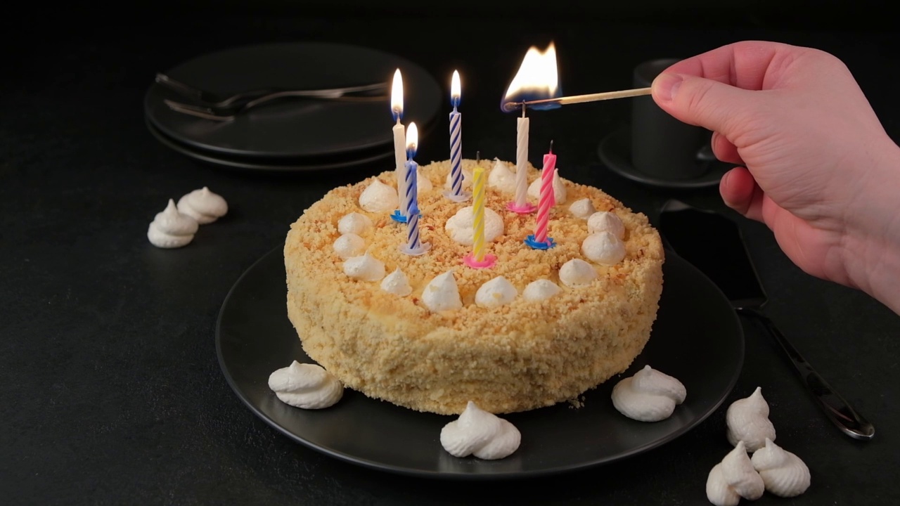 生日蛋糕上全是松软的沙饼屑和迷你蛋白酥皮。一个人在蛋糕上点蜡烛。生日蛋糕着火了视频素材