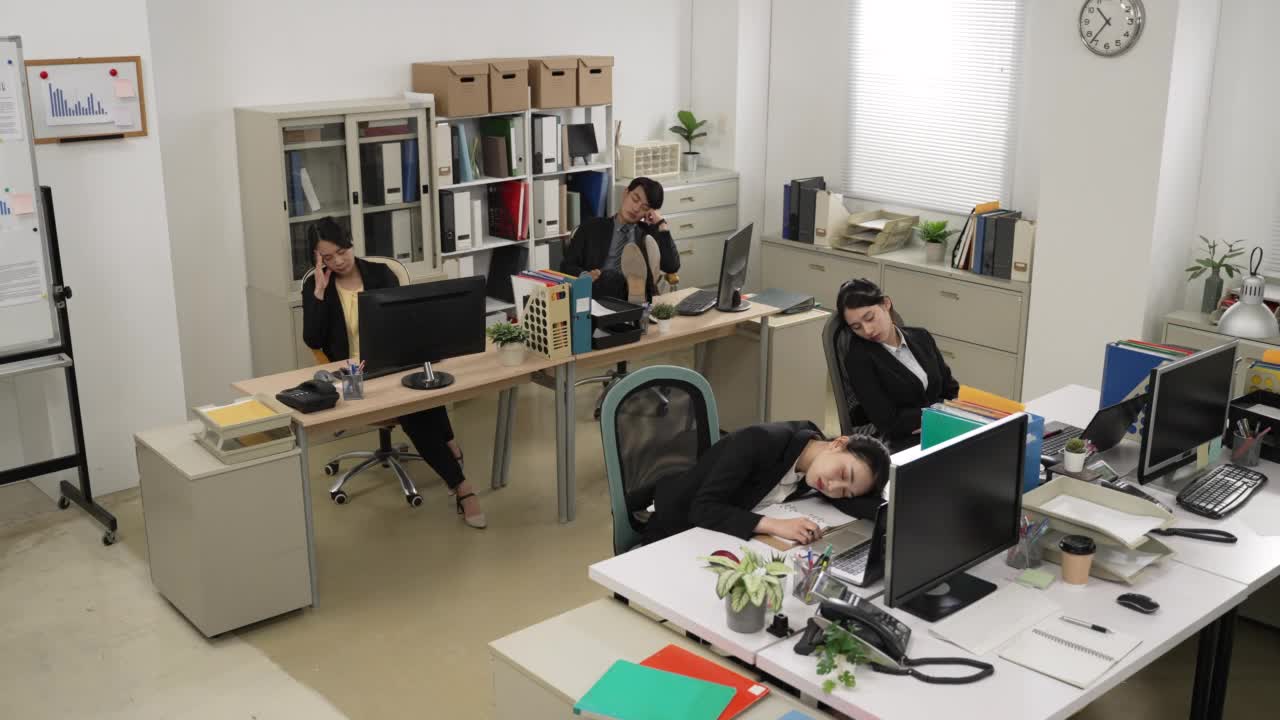 一群疲惫的亚洲商务人士在公司的现代办公室里一起午睡。视频下载