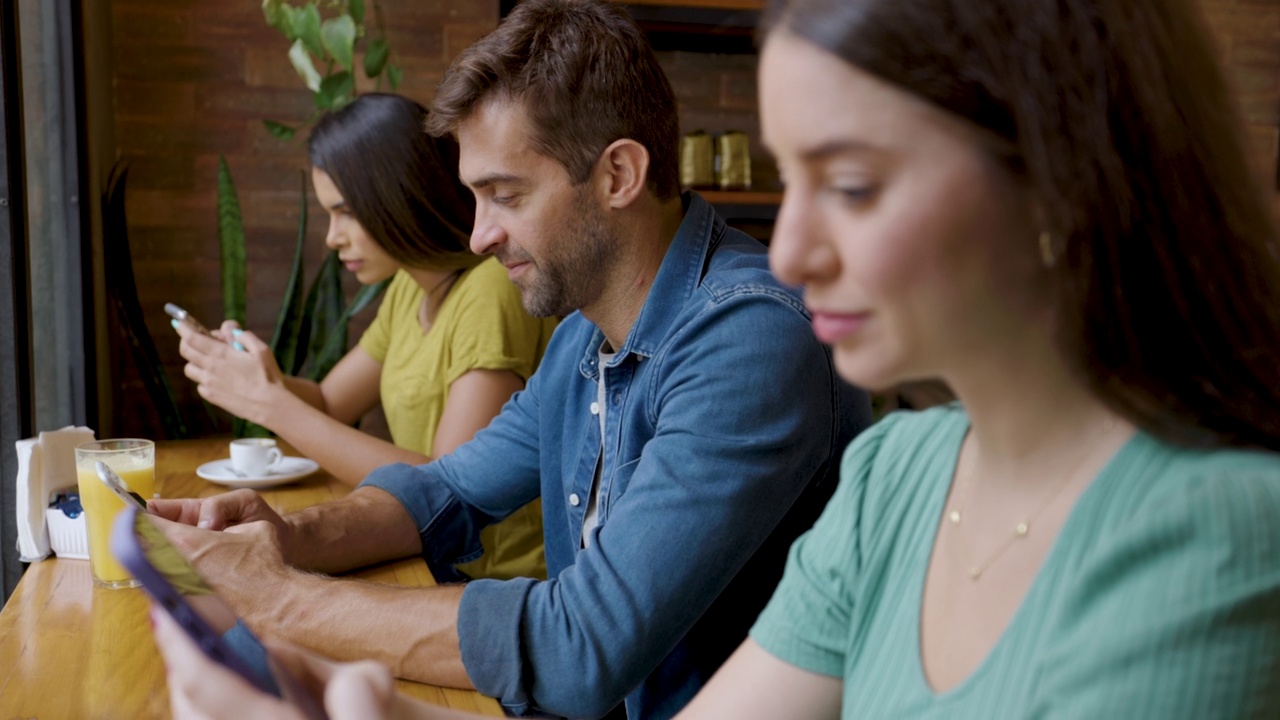 顾客坐在咖啡馆里用智能手机发短信视频素材