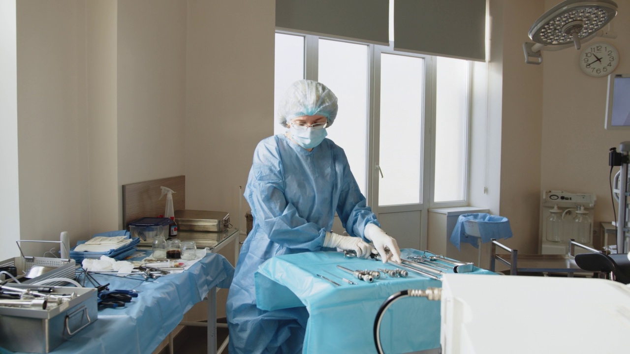 女性医务工作者戴着防护口罩准备手术的肖像。外科器械。准备手术。腹腔镜仪器。腹腔镜设备的使用视频下载