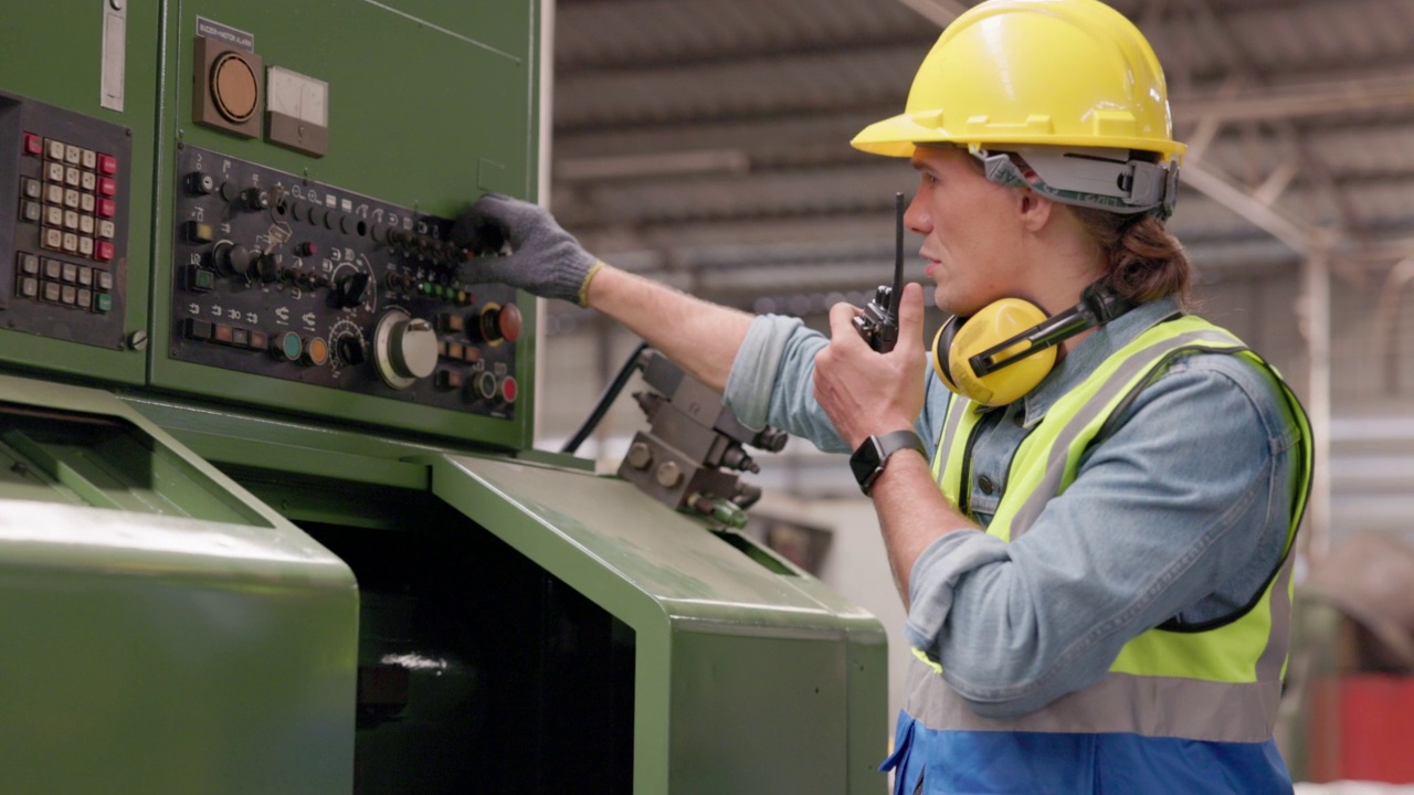 在工厂里，一名工人按下数控机床控制板上的按钮。在一家钢铁厂，视频素材