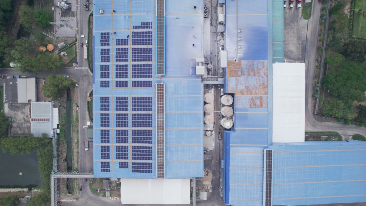 工业加工厂屋顶上安装的蓝色光伏太阳能板鸟瞰图。工厂用可再生能源支持替代能源视频素材