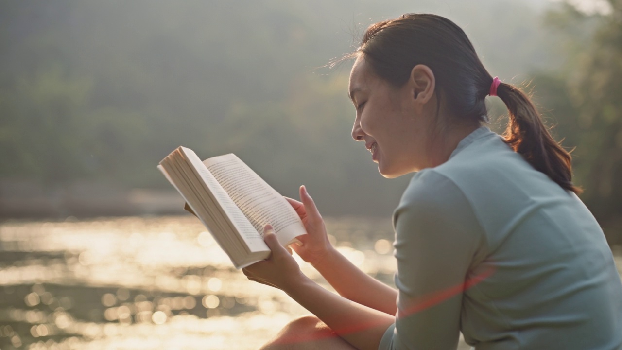 年轻女子在湖边读书放松视频素材