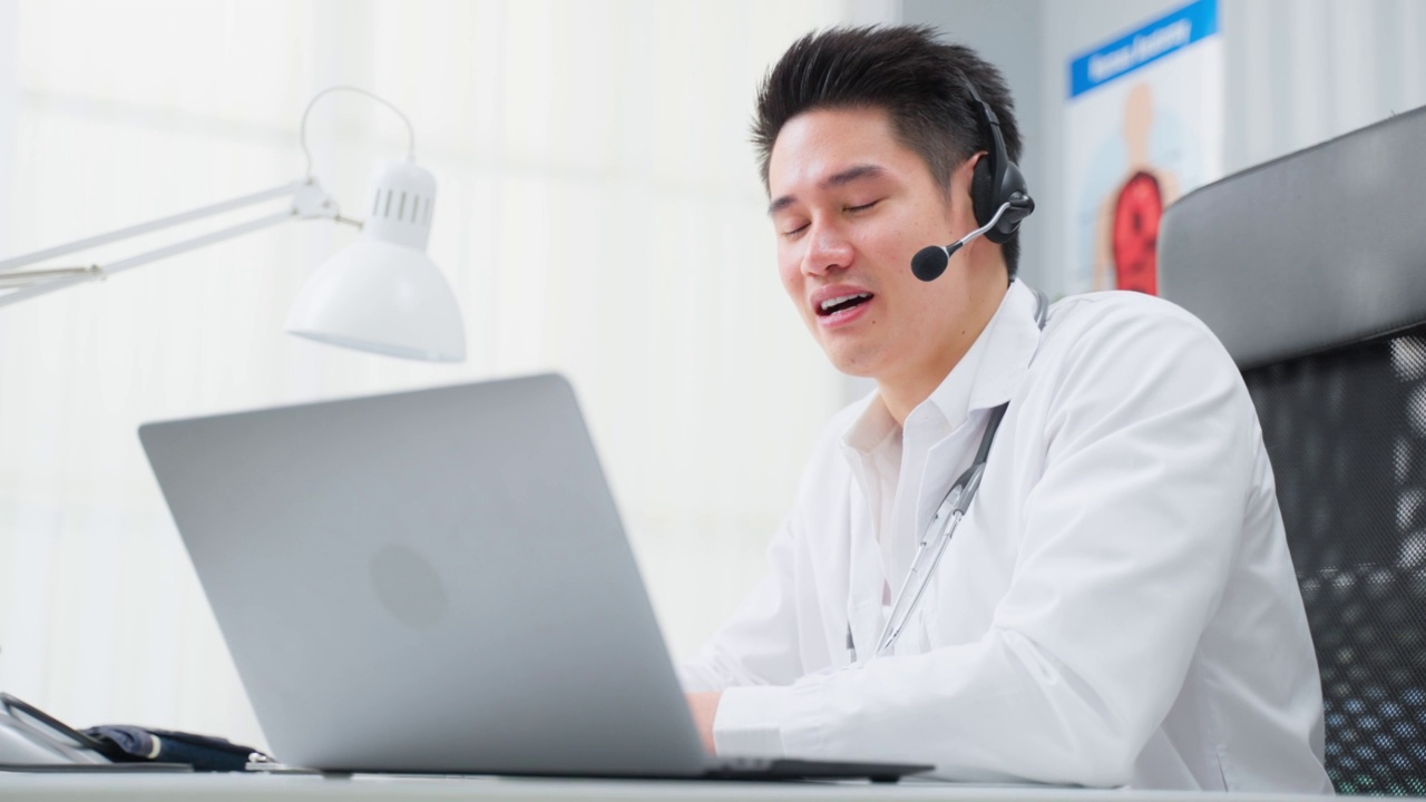 亚洲男性医生在家里与病人进行虚拟在线交谈。迷人的医生在医院远程工作，向病人广播诊断治疗，实现远程健康。视频素材