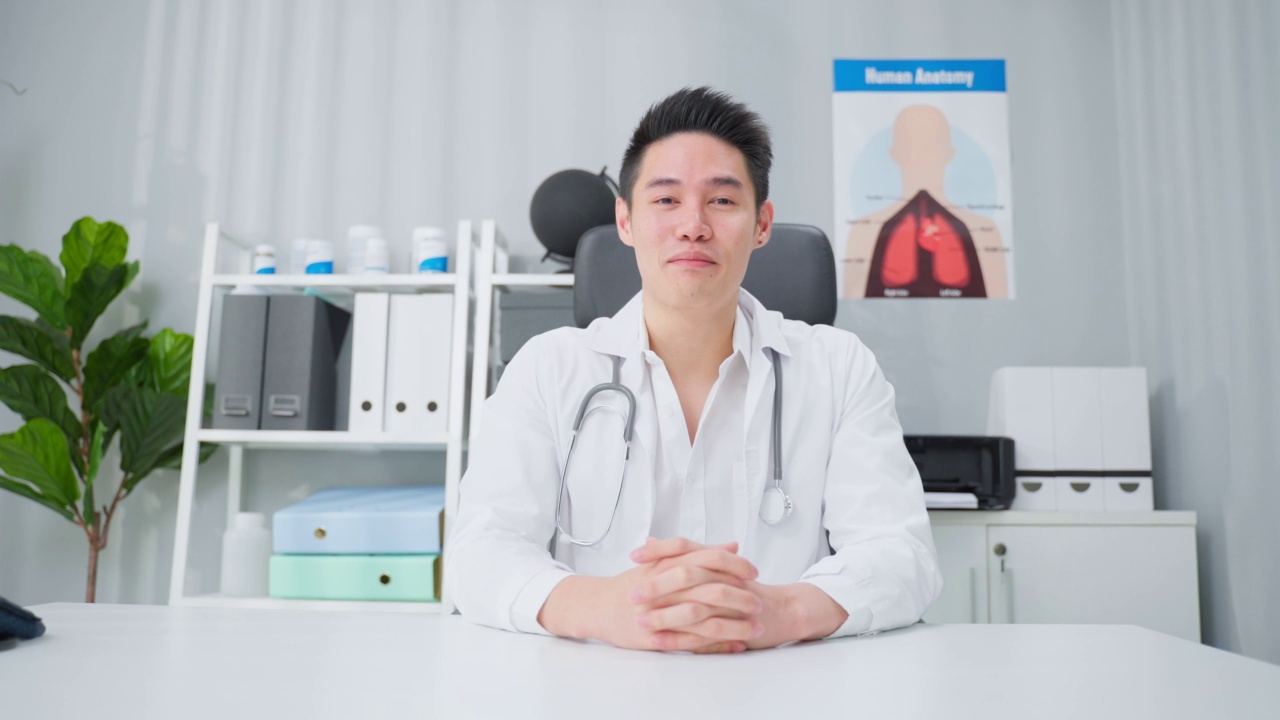 亚洲男性医生在家里与病人进行虚拟在线交谈。迷人的医生在医院远程工作，向病人广播诊断治疗，实现远程健康。视频素材
