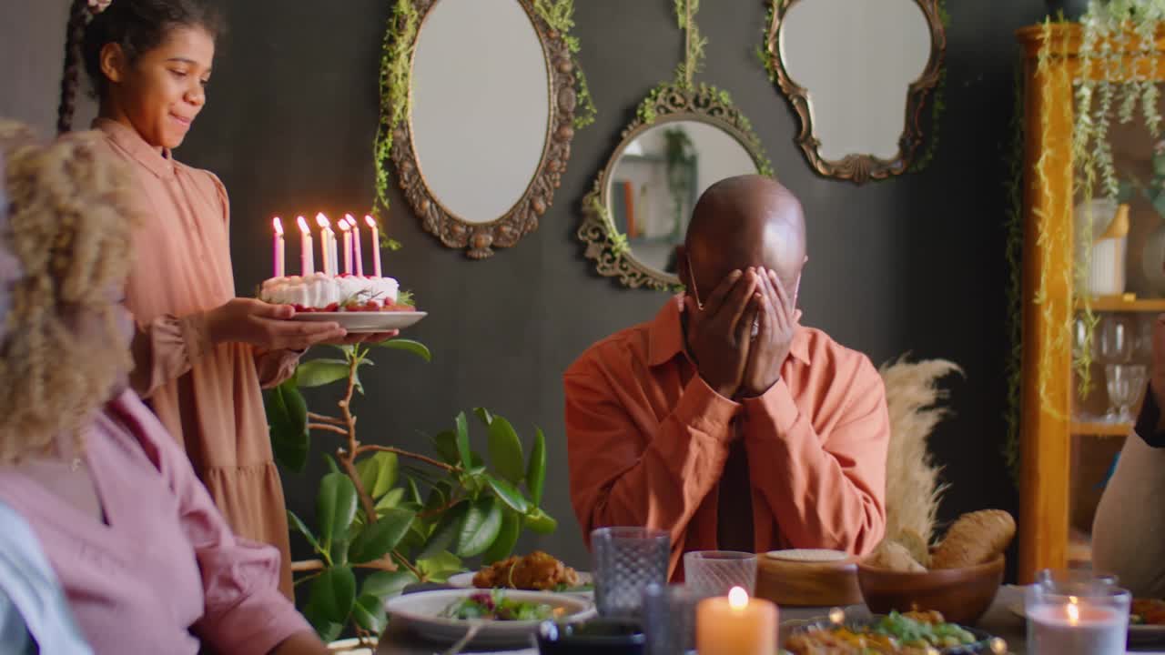 黑人男子在家里的生日蛋糕上吹蜡烛视频素材