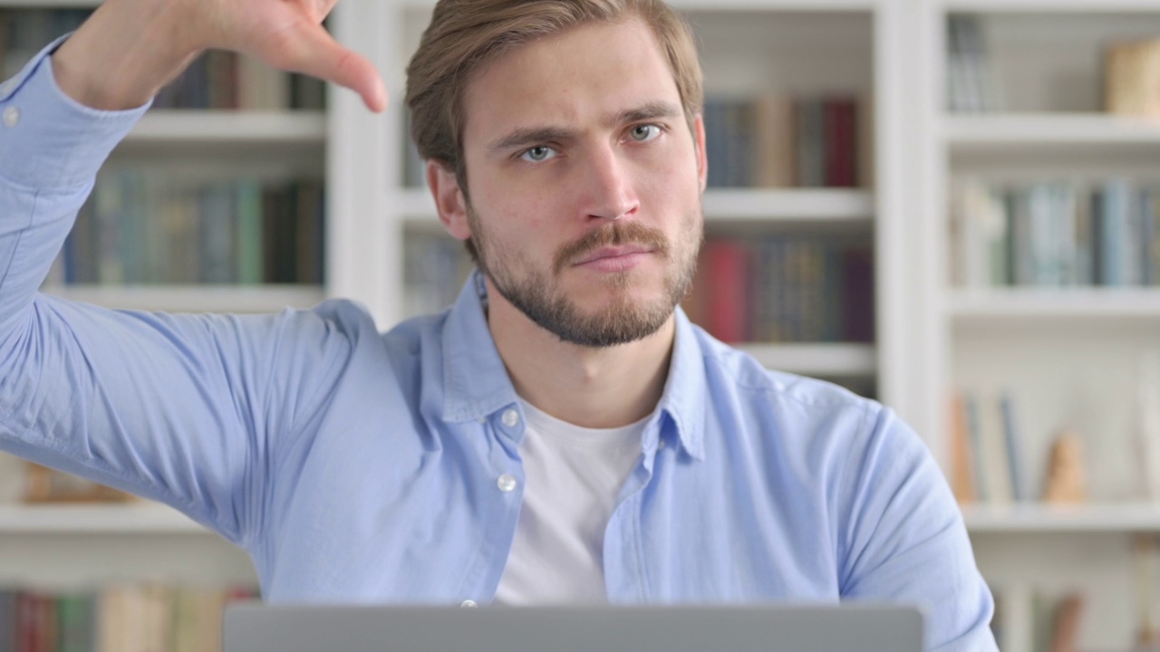 男子在使用笔记本电脑时显示拇指向下的特写视频素材