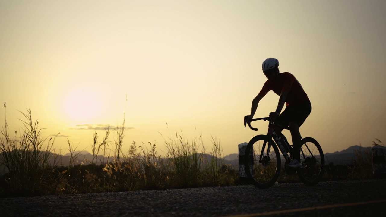 运动的人通过骑自行车在乡间的公路自行车来锻炼身体视频下载
