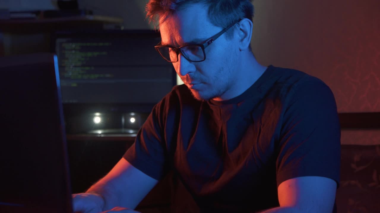 一个男人的肖像在黑暗的房间里，戴着眼镜对着电脑类型的概念想法视频下载