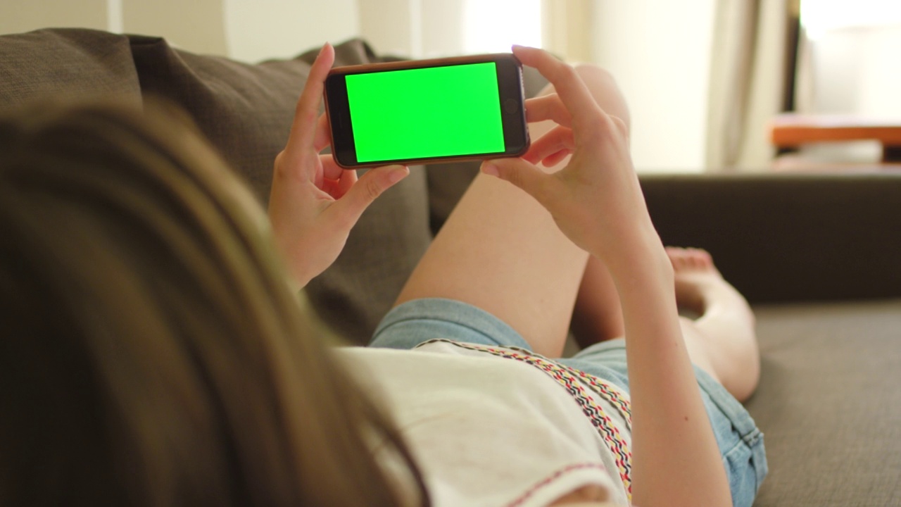一个女人躺在沙发上用智能手机的4k视频视频素材