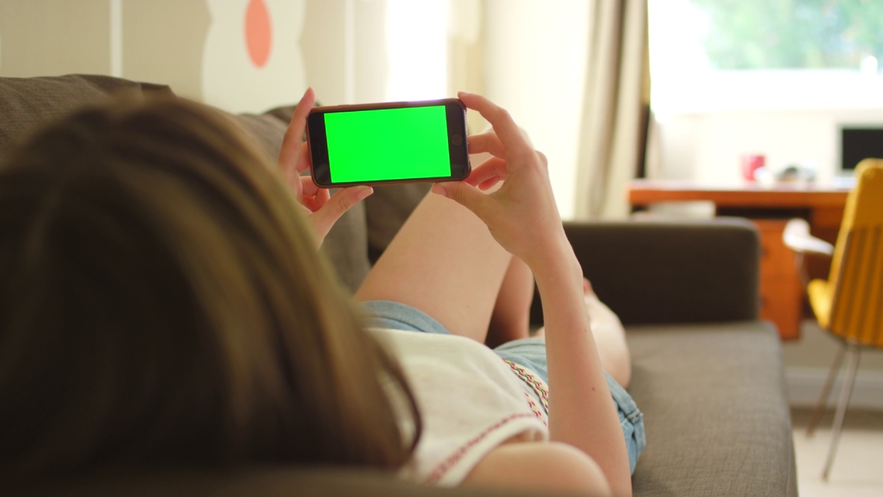 一个女人躺在沙发上用智能手机的4k视频视频素材