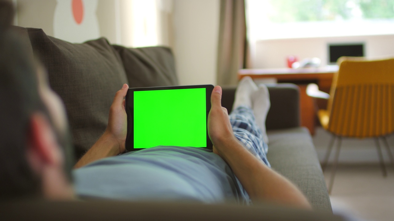 一名男子躺在沙发上使用数字平板电脑的4k视频视频素材