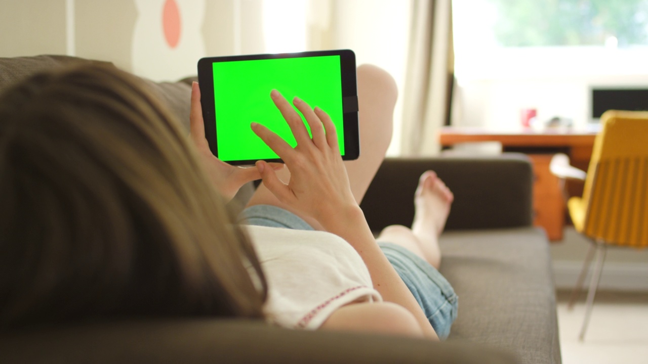 一个女人躺在沙发上用数字平板电脑的4k视频视频素材