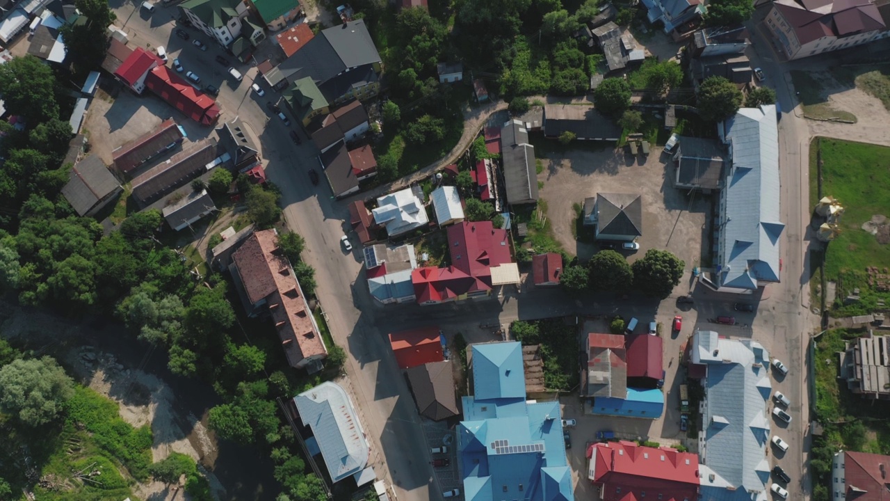 从上往下鸟瞰一个小镇的房屋屋顶，有河流、树木和汽车。视频下载
