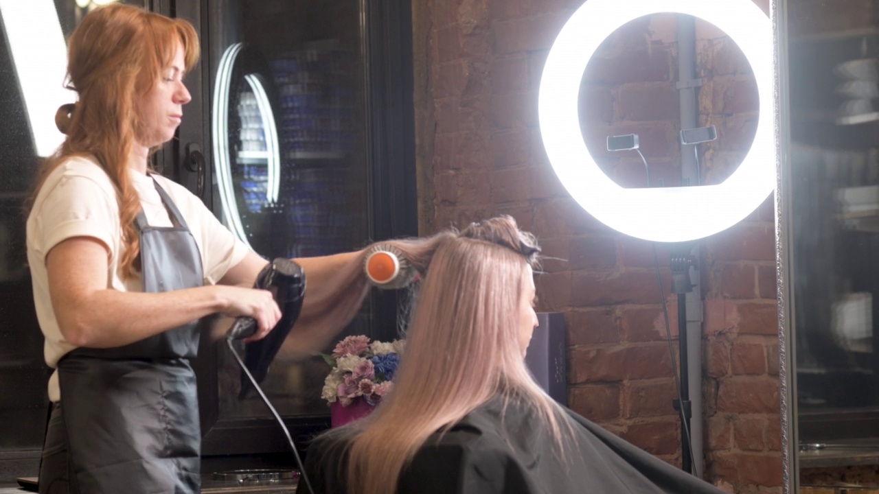 工作室的美发师用吹风机为女顾客吹头发视频素材