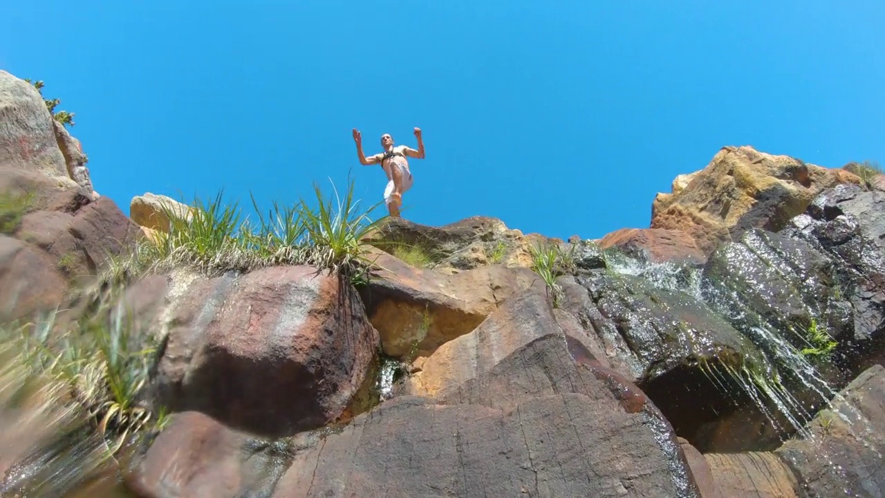 南非，一名男子从阳光灿烂的瀑布岩石上跳入游泳池视频下载