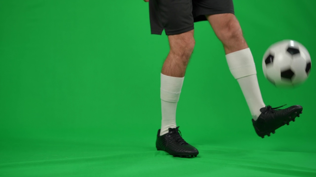 在绿色屏幕上抛接足球的陌生男子。年轻自信的白人运动员在chromakey训练的双腿背景模型。技能和运动概念。视频素材