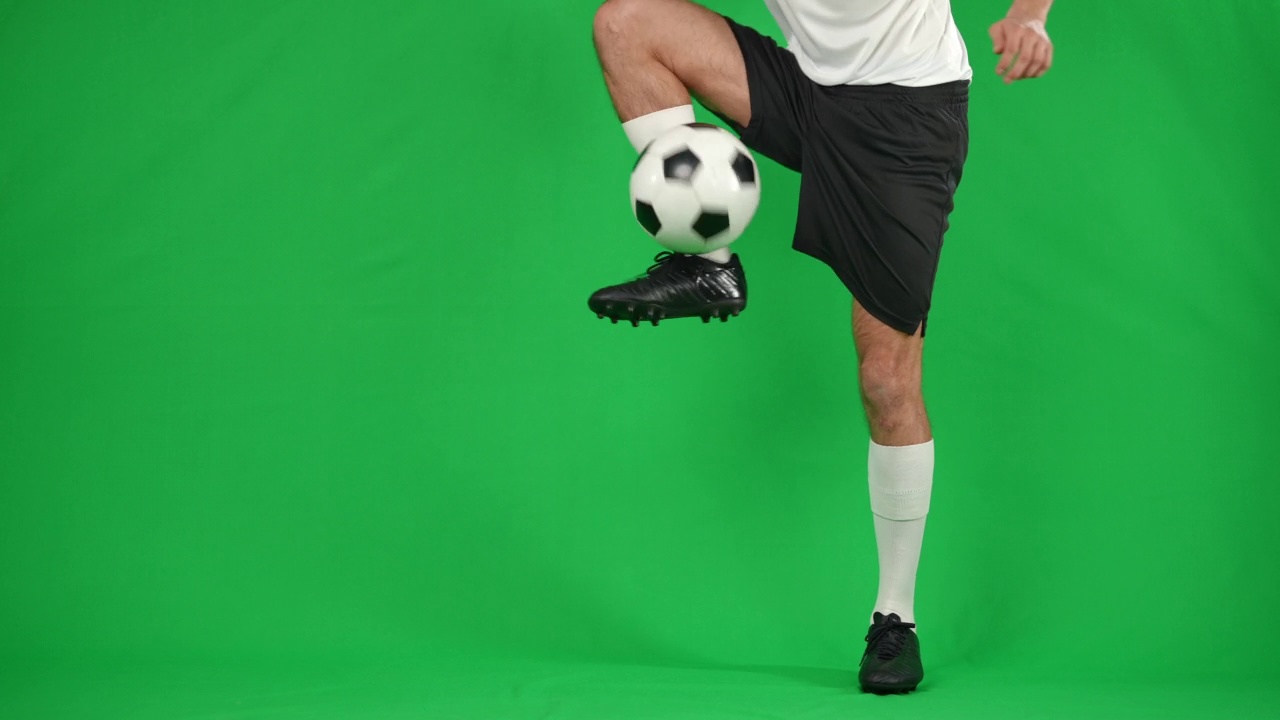 在绿色屏幕上用慢动作捕捉传球的白人运动员。年轻的职业足球运动员玩游戏在chromakey背景。视频素材