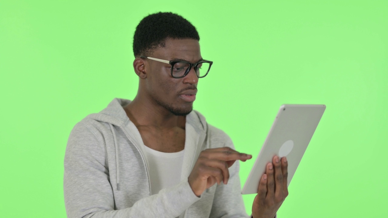 非洲男子在绿色背景下对平板电脑损失的反应视频素材
