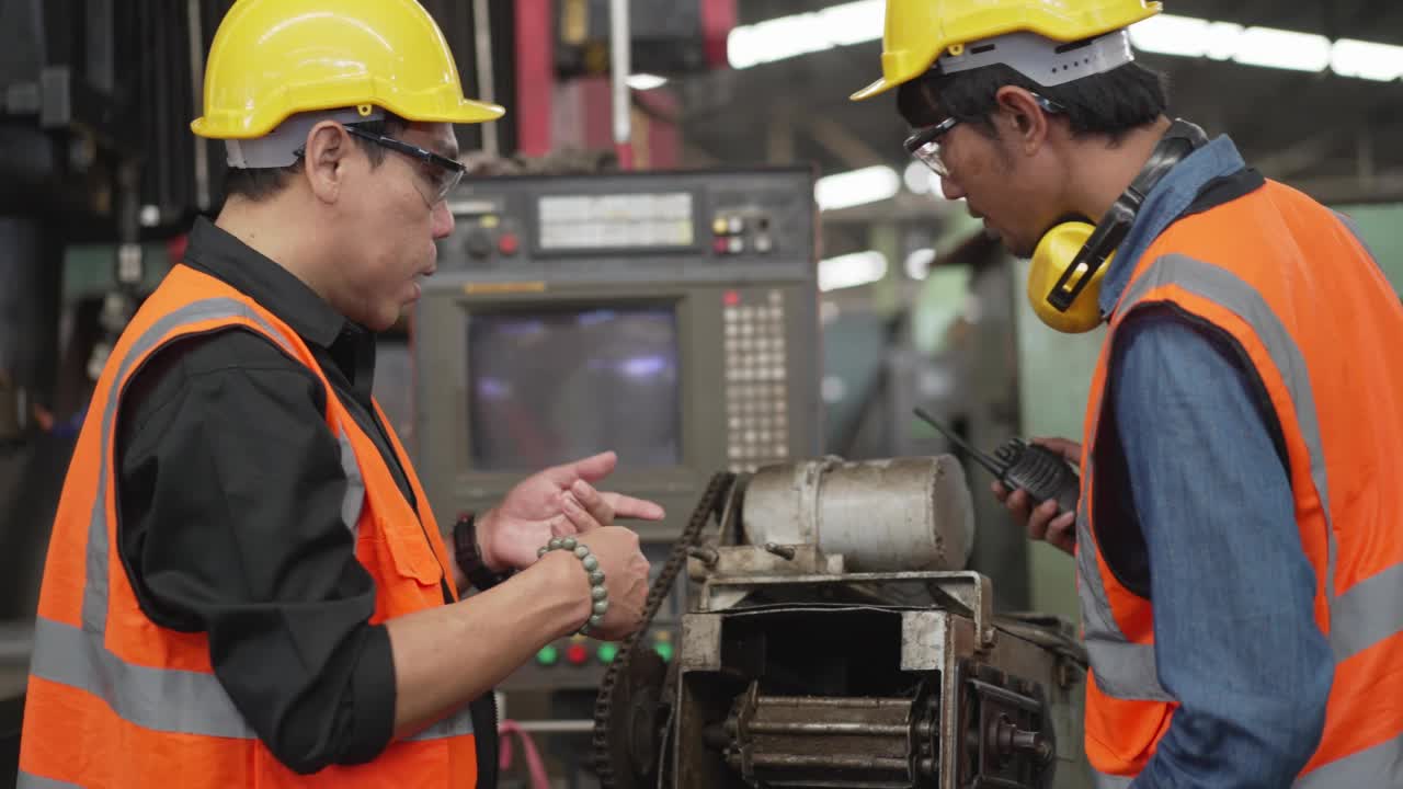 亚洲男工厂工人操作控制大型机器，在工业建设中与同事一起工作和讨论。维修和保养机器。安全工作性能。视频素材