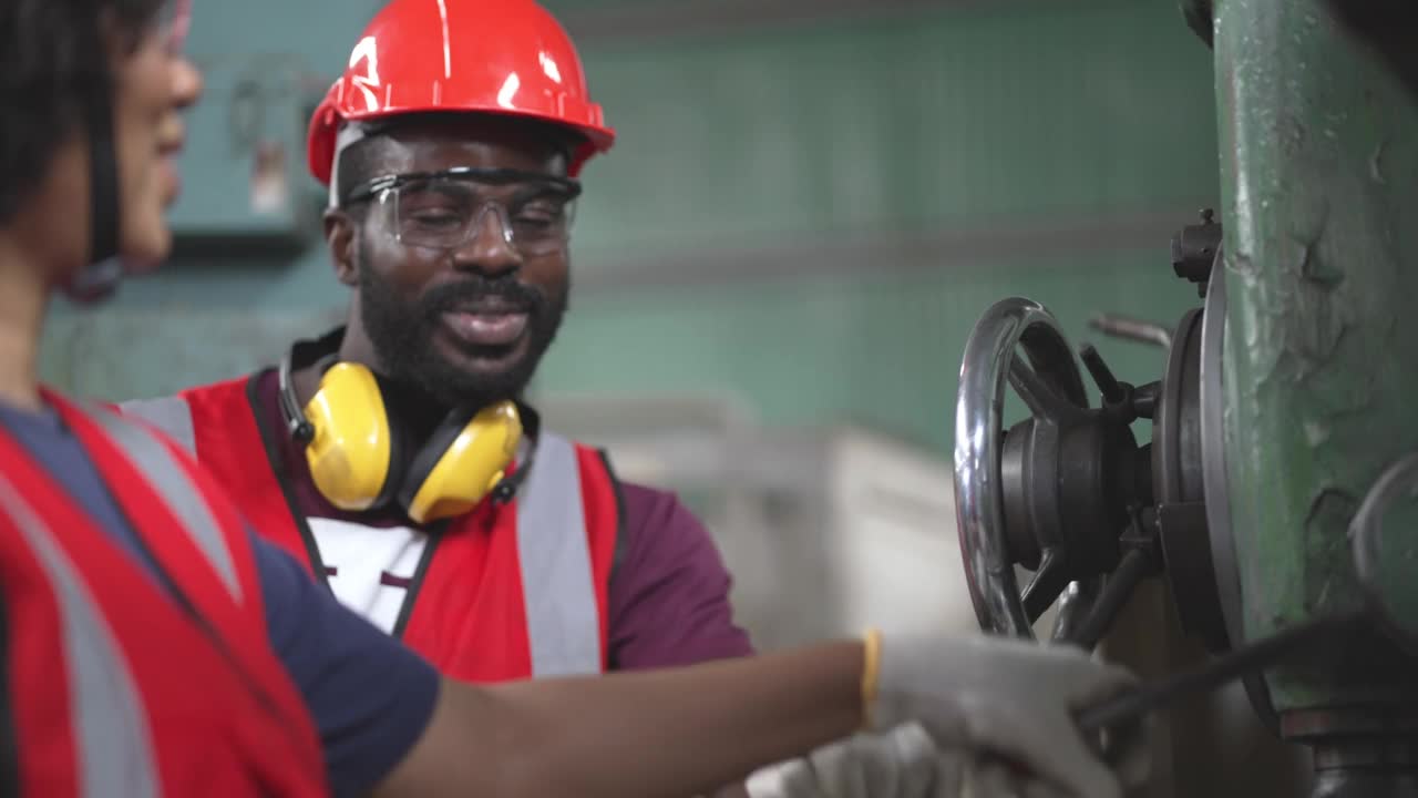 非裔美国男性工厂工人操作控制大机器，在工业建设中与同事一起工作和讨论。维修和保养机器。安全工作性能。视频素材