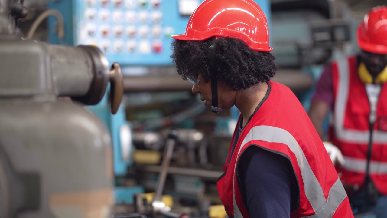 在工业工厂中穿着安全制服检查和控制大型机器的非裔美国女工。在建筑工地工作的妇女。视频素材