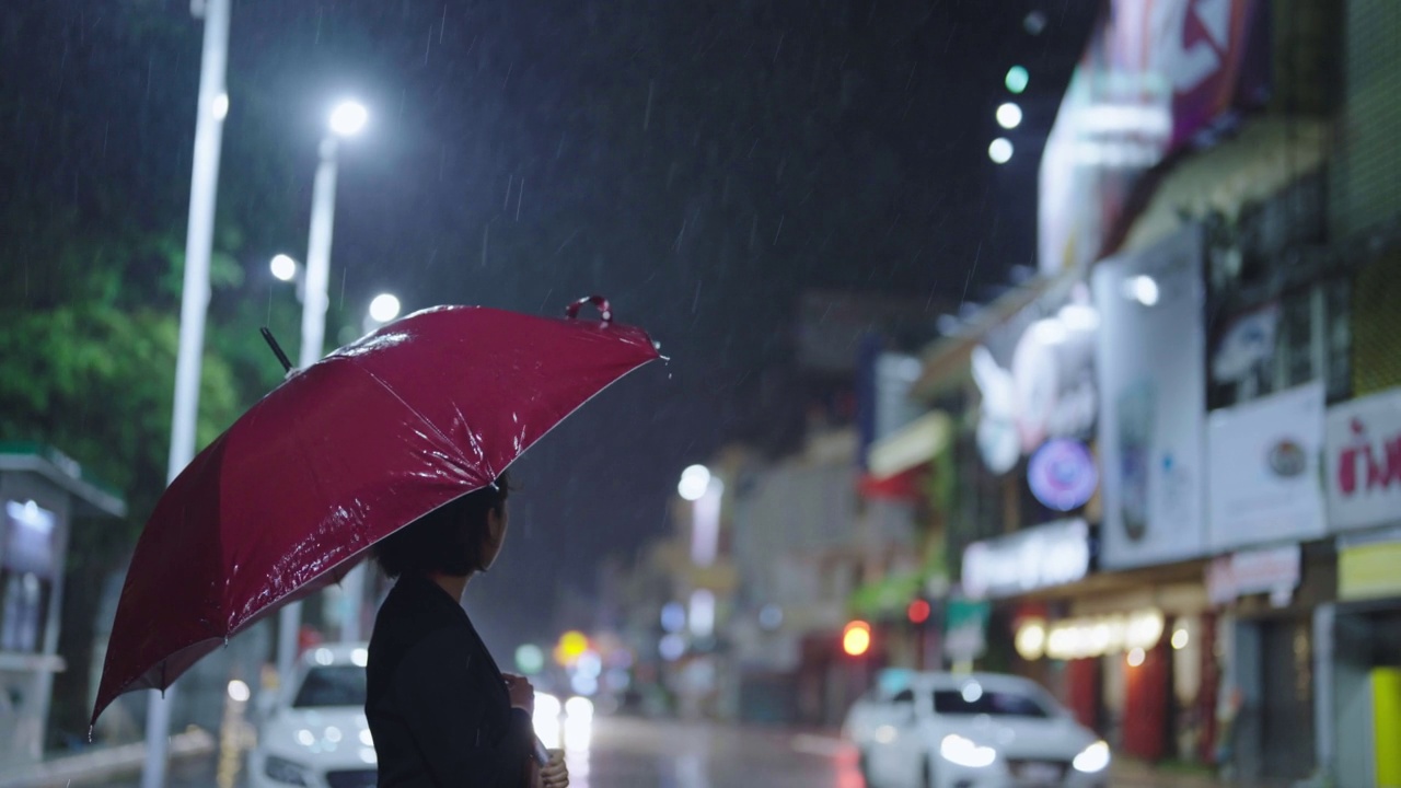 在雨中，一位亚洲妇女撑着一把伞。视频下载