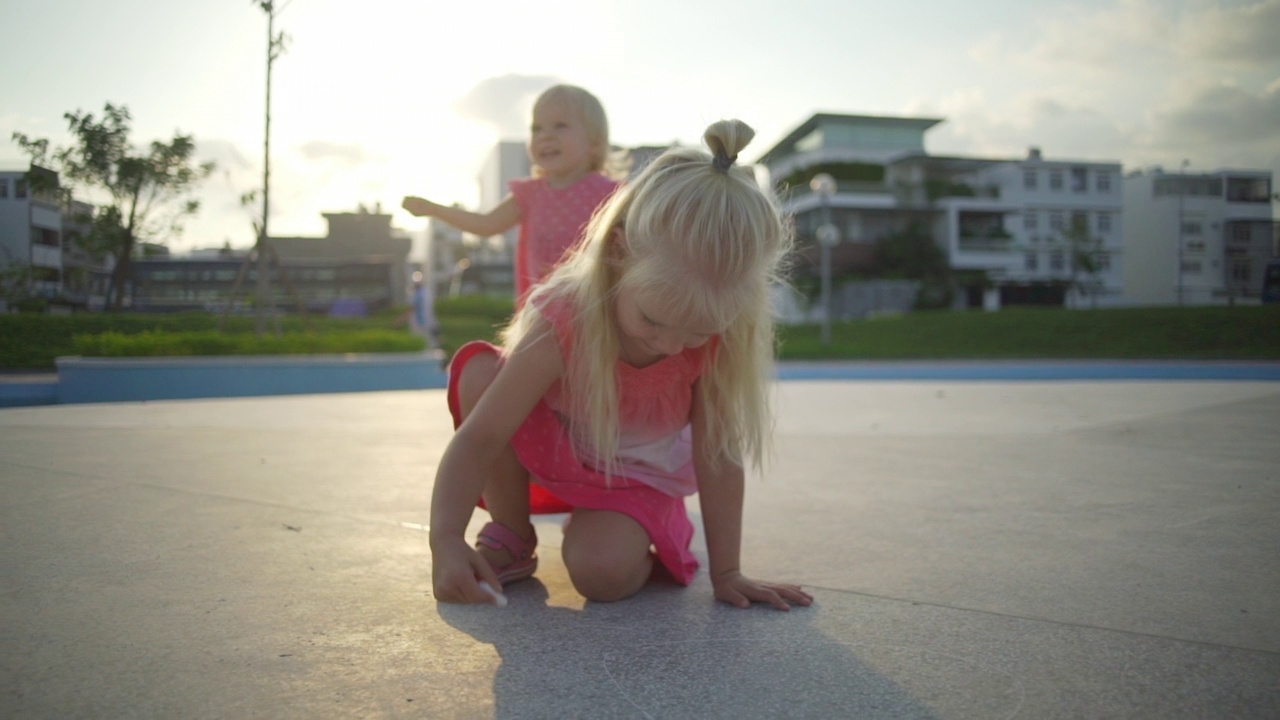 金发小女孩在操场上画粉笔在日出时快速慢动作视频素材