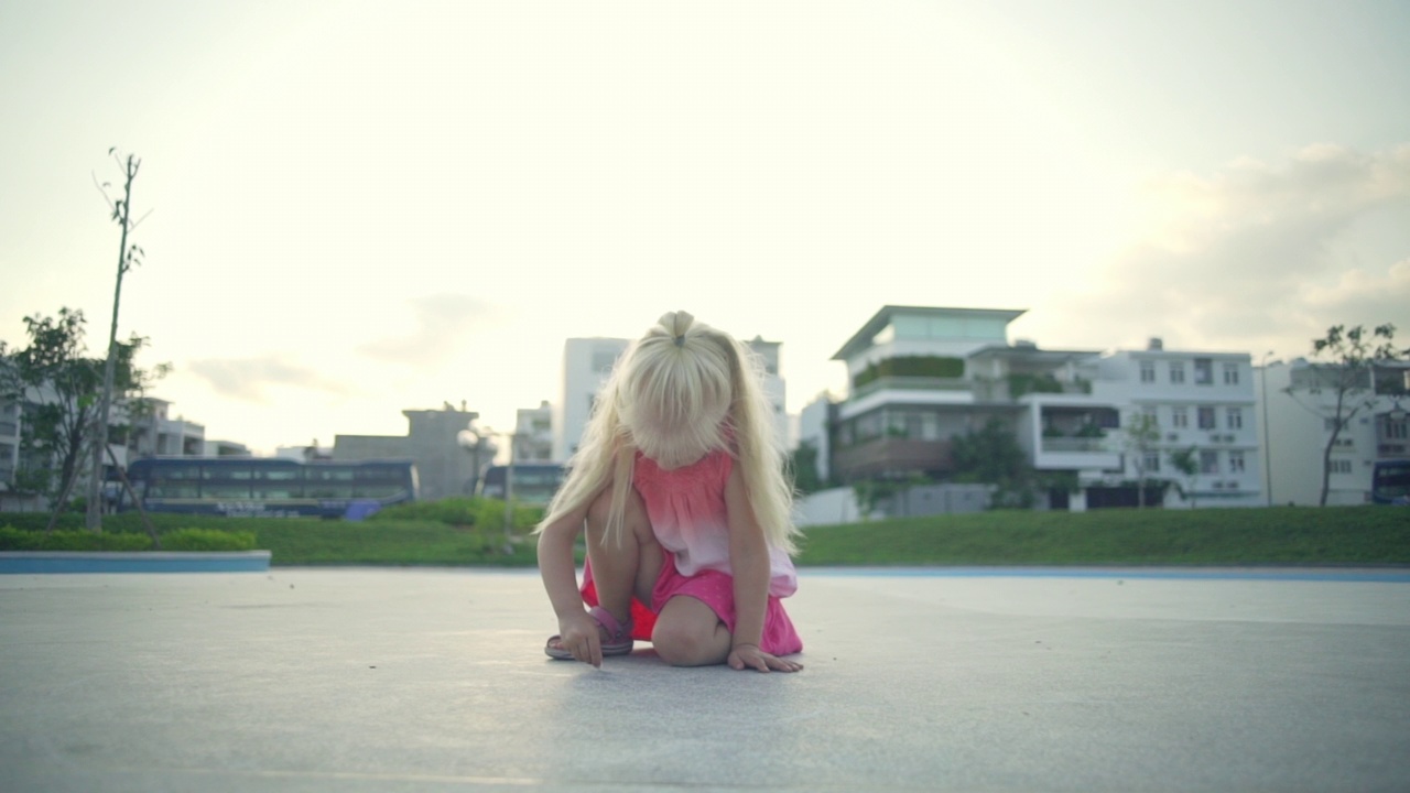 金发小女孩在操场上画粉笔在日落快速慢动作视频素材