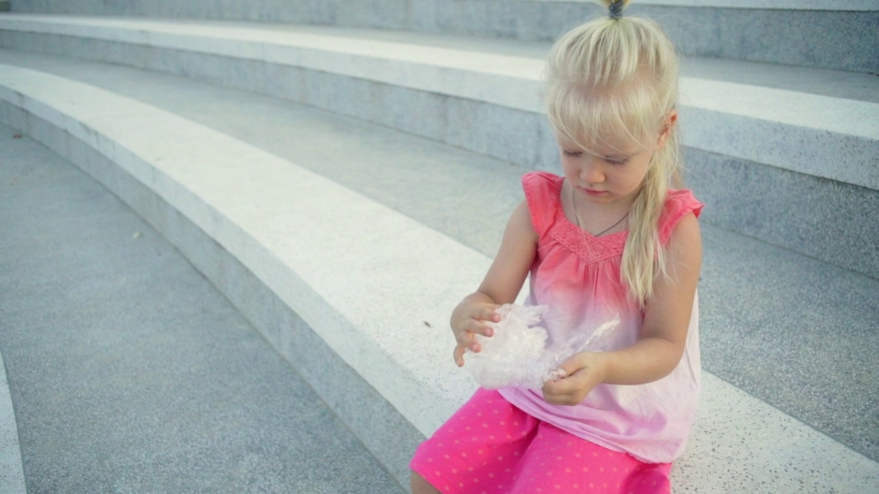 专注的女婴玩泡沫包装在楼梯日落快速慢动作视频素材