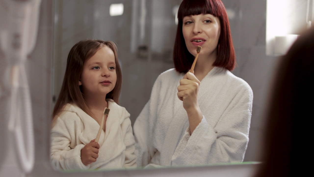 妈妈和她的小可爱看着镜子，对着牙刷在麦克风里唱歌视频素材