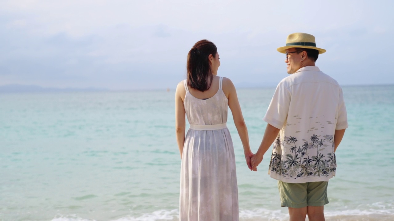 4K幸福的亚洲夫妇牵手，一起走在热带海滩在夏天的日落视频素材