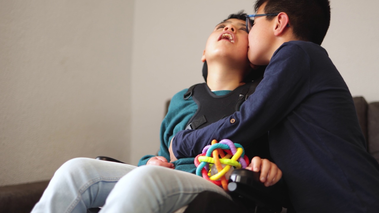 孩子与坐轮椅的残疾弟弟在一起的温馨时刻-家庭爱的概念视频下载