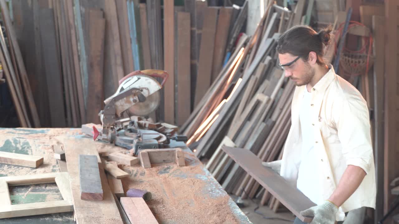 木匠正在车间工作。他正在锯一块木板。视频素材