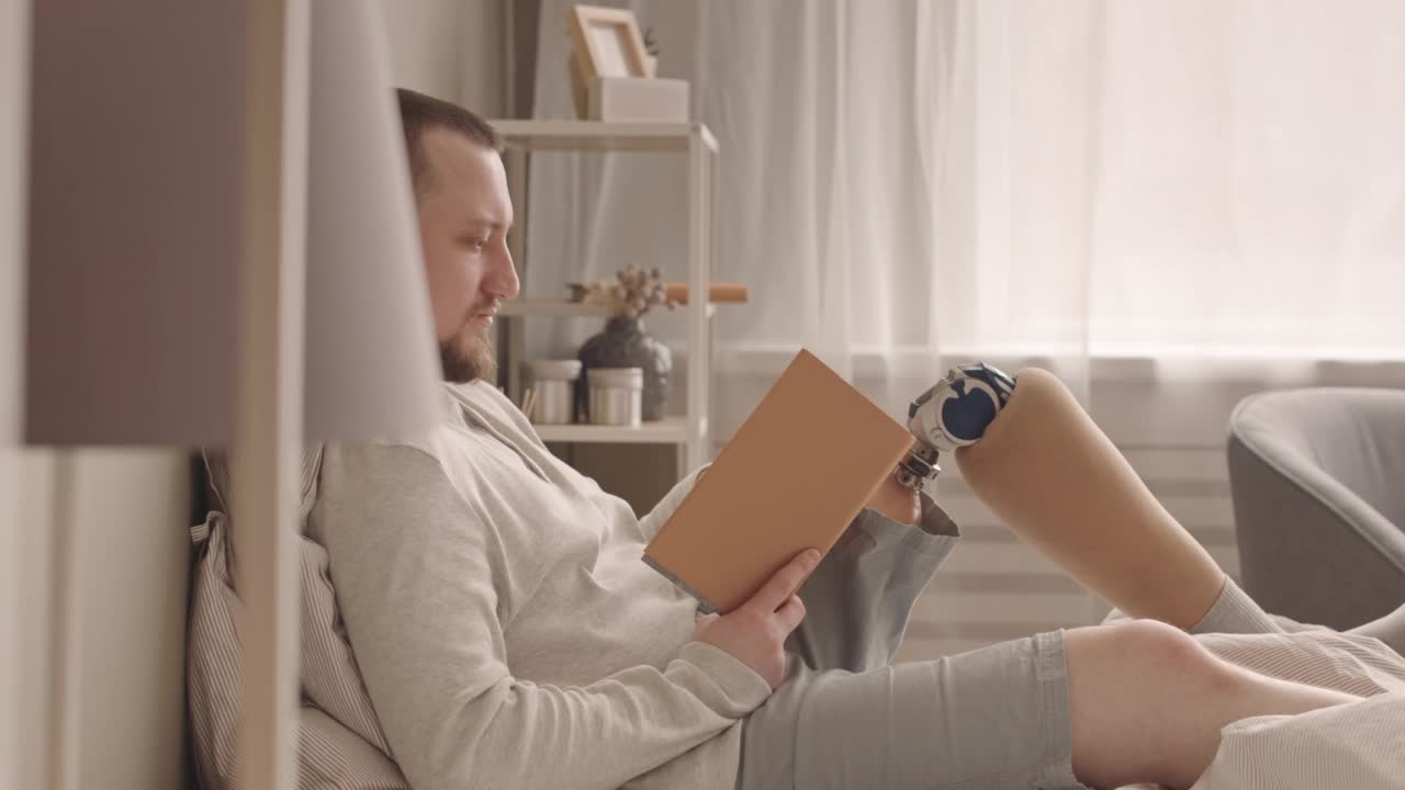 一个装了假肢的男人躺在床上看书视频下载
