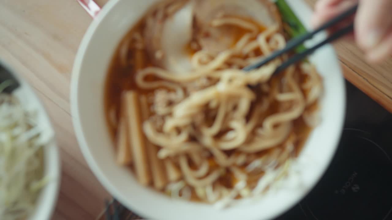 高角度观手用筷子挑热汤用辣椒汤拉面和日式tsukemen面。视频下载