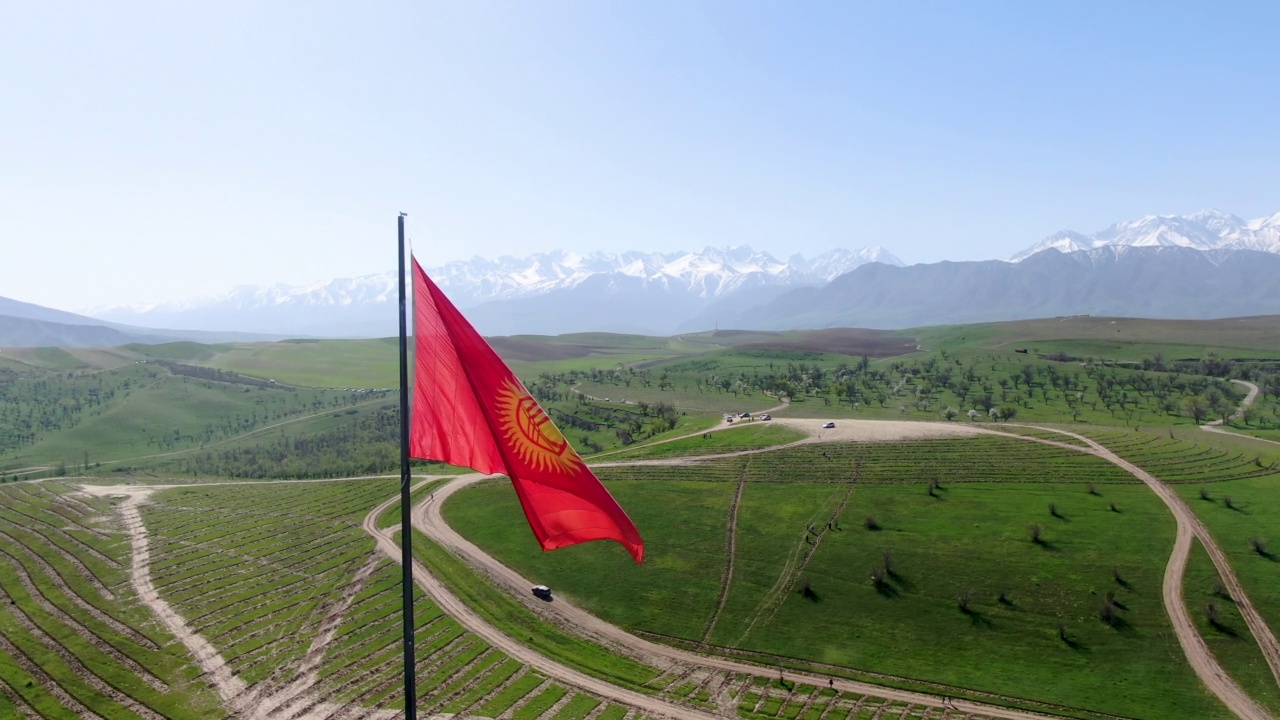 吉尔吉斯斯坦国旗在旗杆上飘扬，背景是雪山视频下载