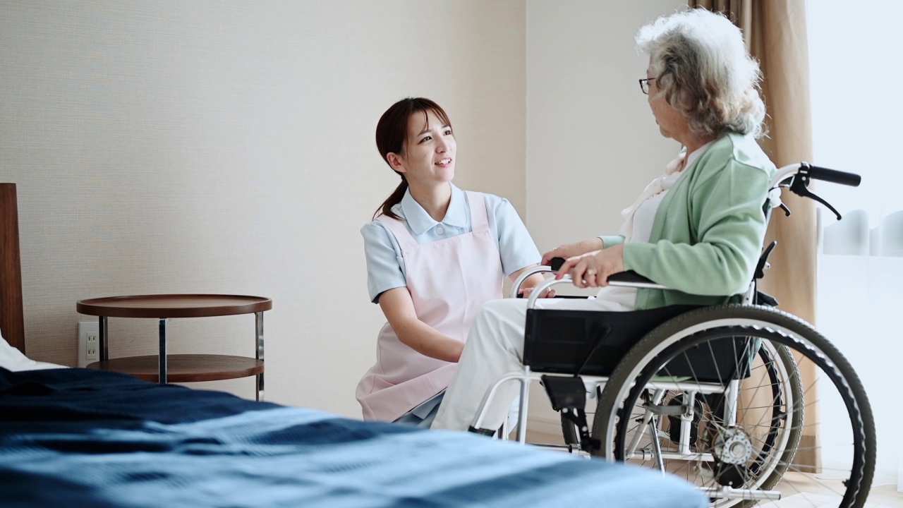 在养老院帮助坐轮椅的老年妇女的年轻女性护工。视频素材