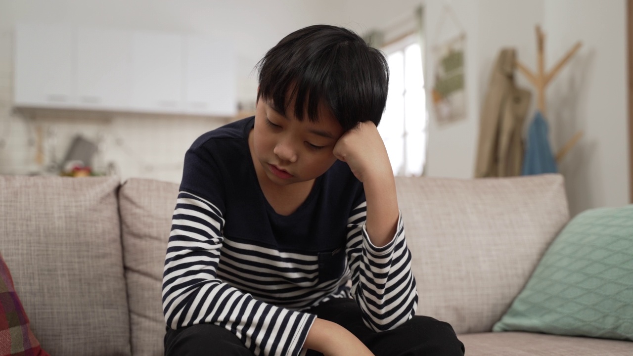 年轻的亚洲青少年男孩感到抑郁在他的卧室，网络欺凌的孩子，抑郁的儿童心理健康，社会距离的概念视频素材