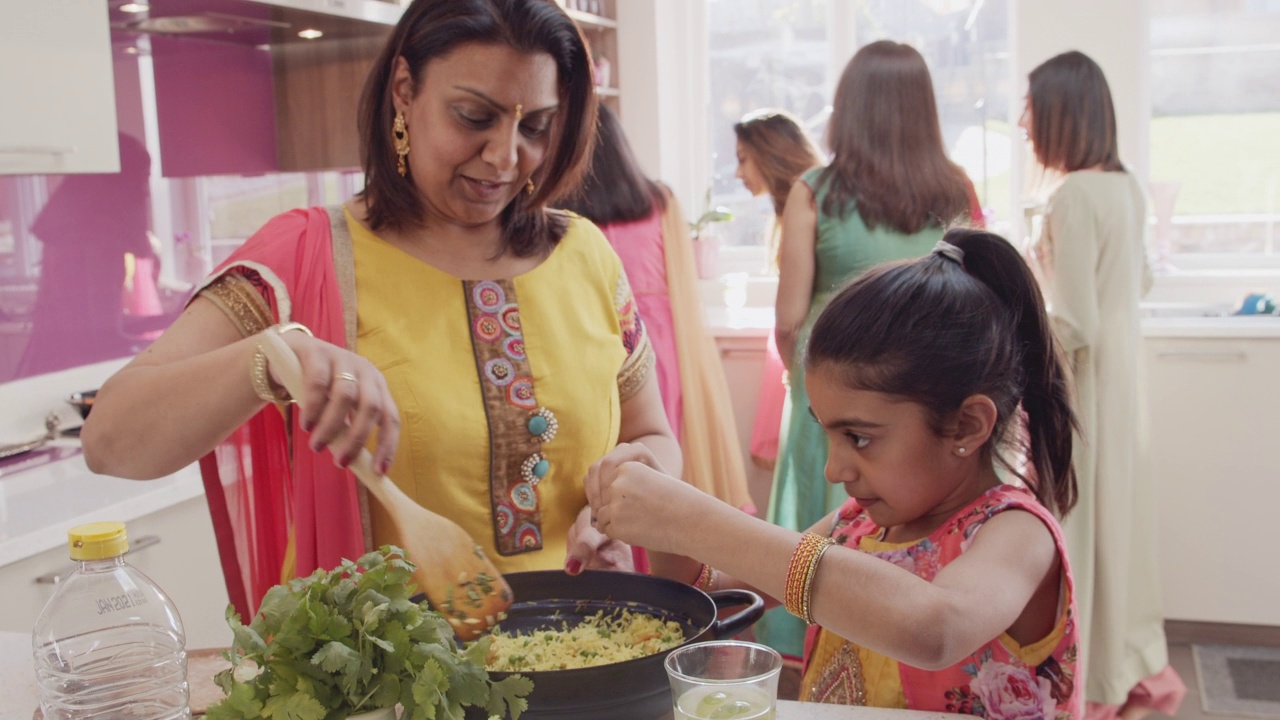 印度母女穿着纱丽在厨房做饭视频素材