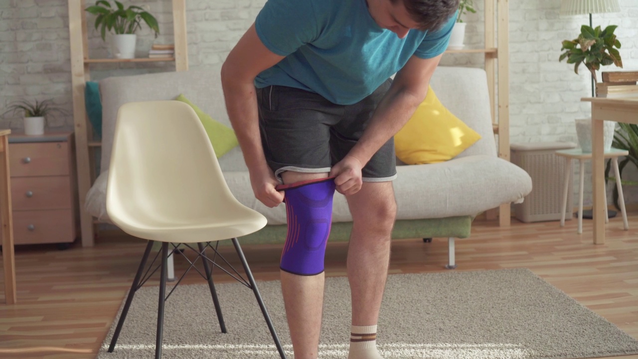 一名男子运动员在受伤后扯下膝盖上的绷带。运动损伤的概念视频素材