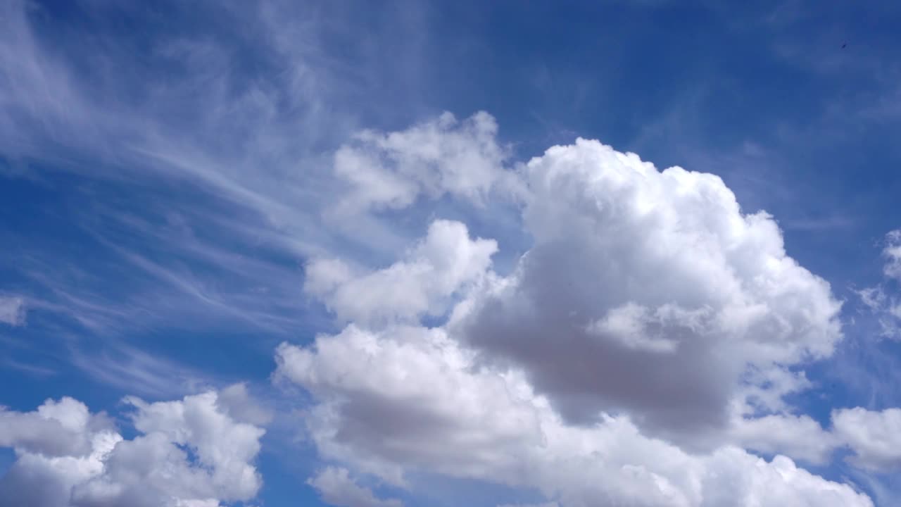 美丽的蓬松的白色积云和缕缕，羽毛卷云漂浮在灿烂的蓝天视频下载
