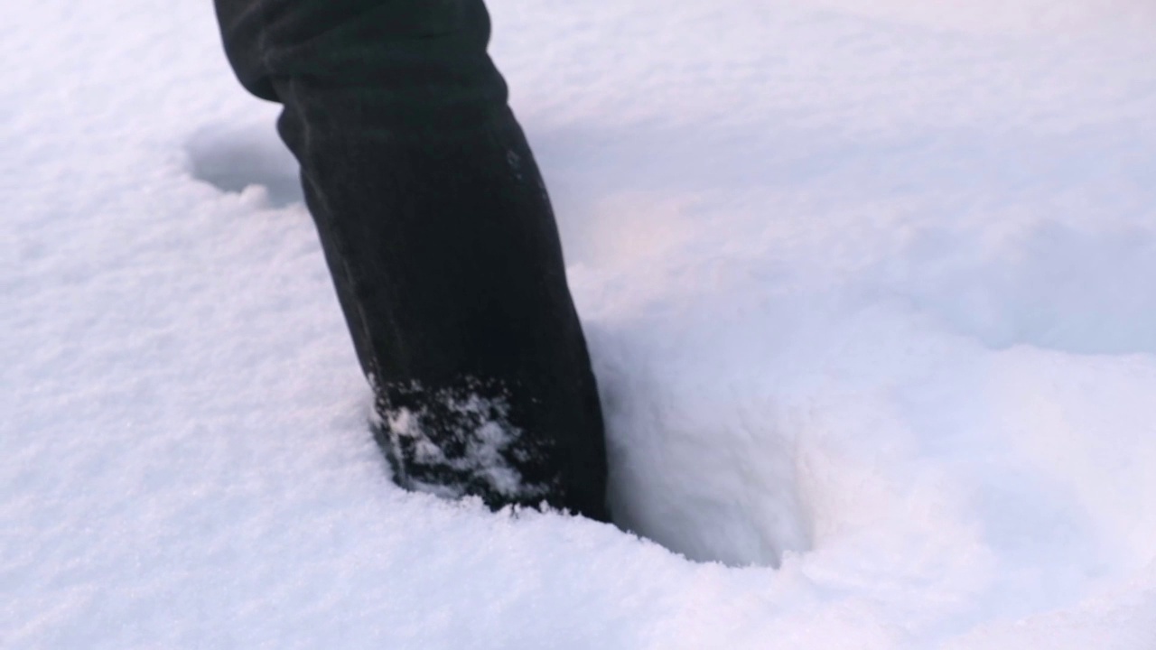 一个穿靴子的人走过雪堆。视频下载