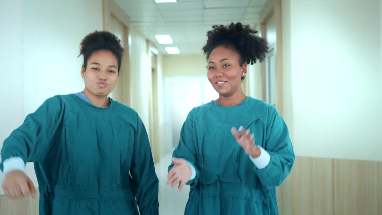 快乐的非裔美国护士和助理在医院的走廊上跳舞。有享受的医务人员。视频素材