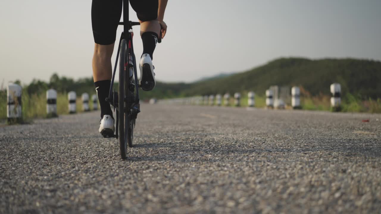 运动的人通过骑自行车在乡间的公路自行车来锻炼身体视频下载