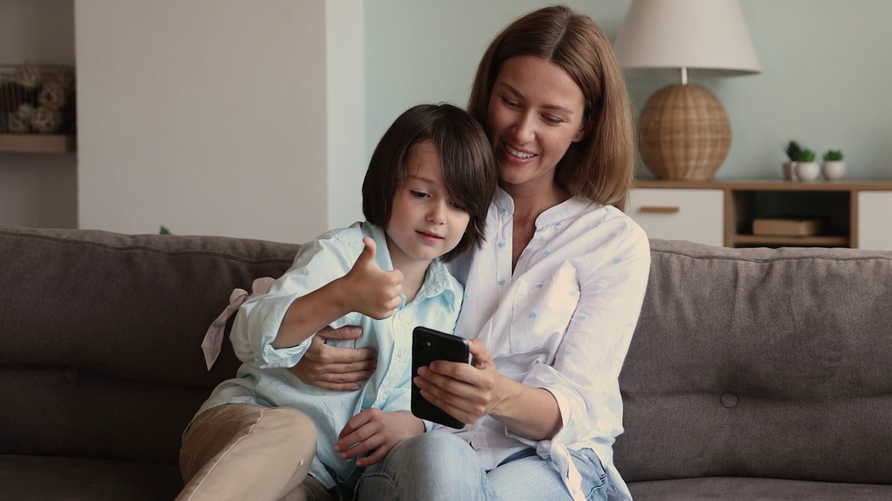 小男孩和妈妈使用智能手机享受新的移动应用程序视频下载