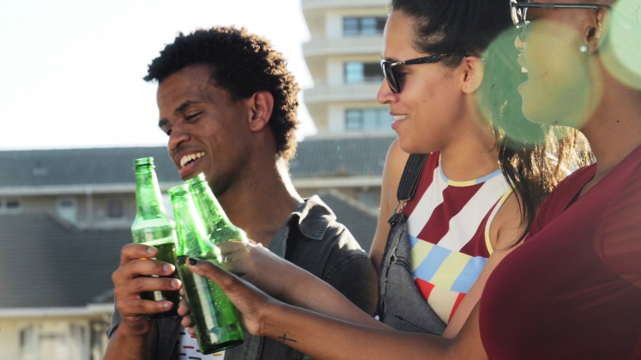 年轻的朋友们在阳光明媚的城市阳台上喝啤酒视频下载